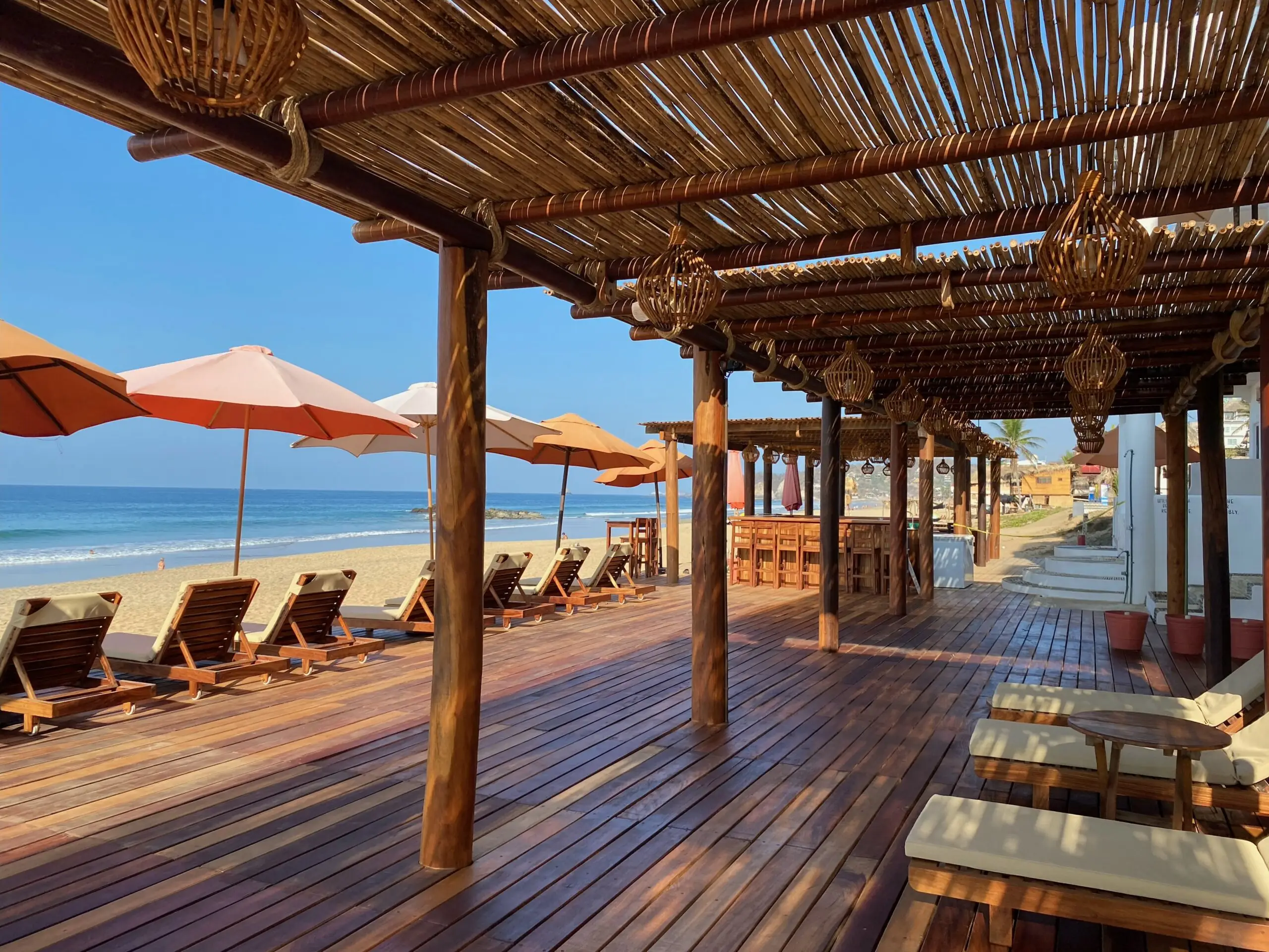 Terraza de madera con camastros y sombrillas frente al mar