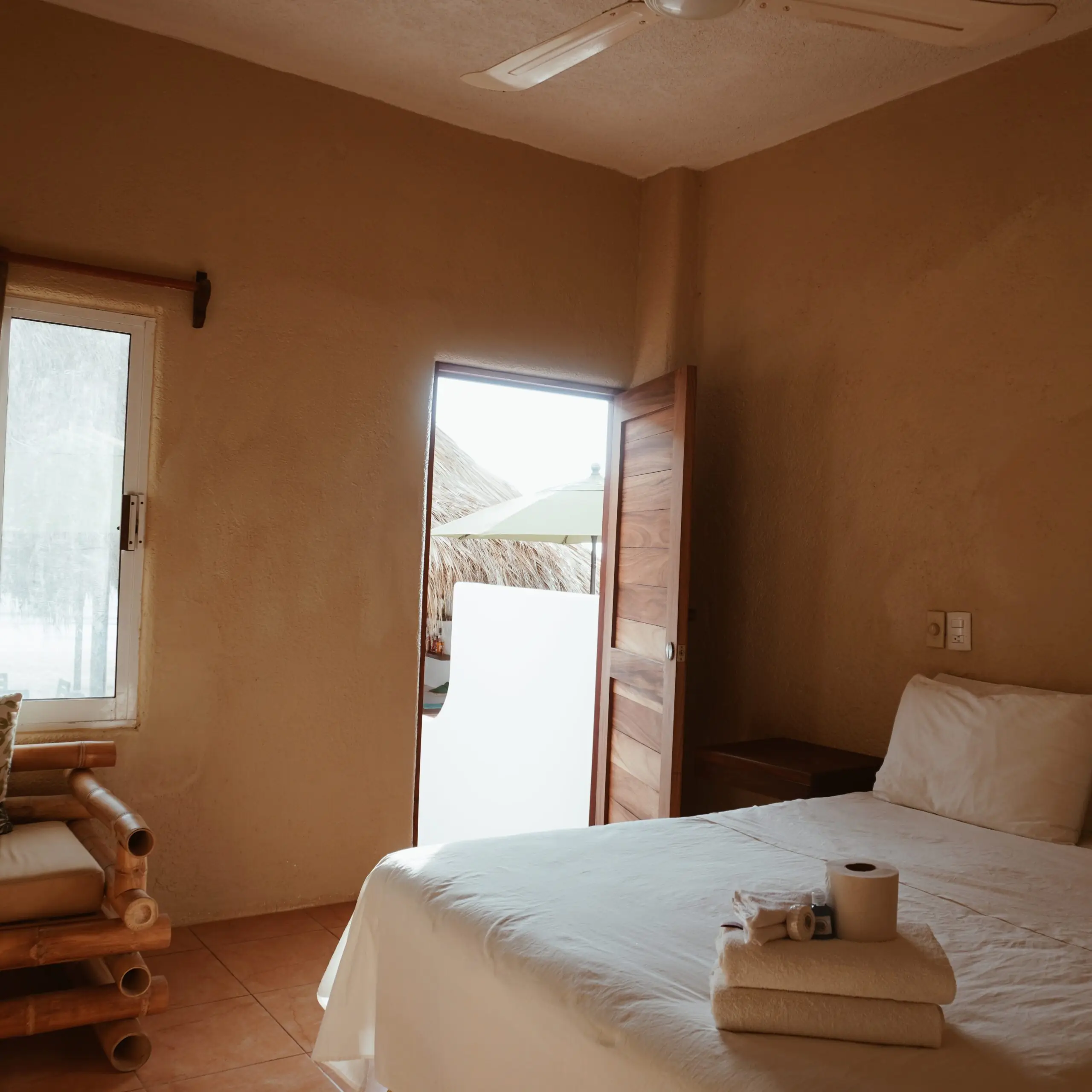 Cama matrimonial con toallas y salida a la terraza